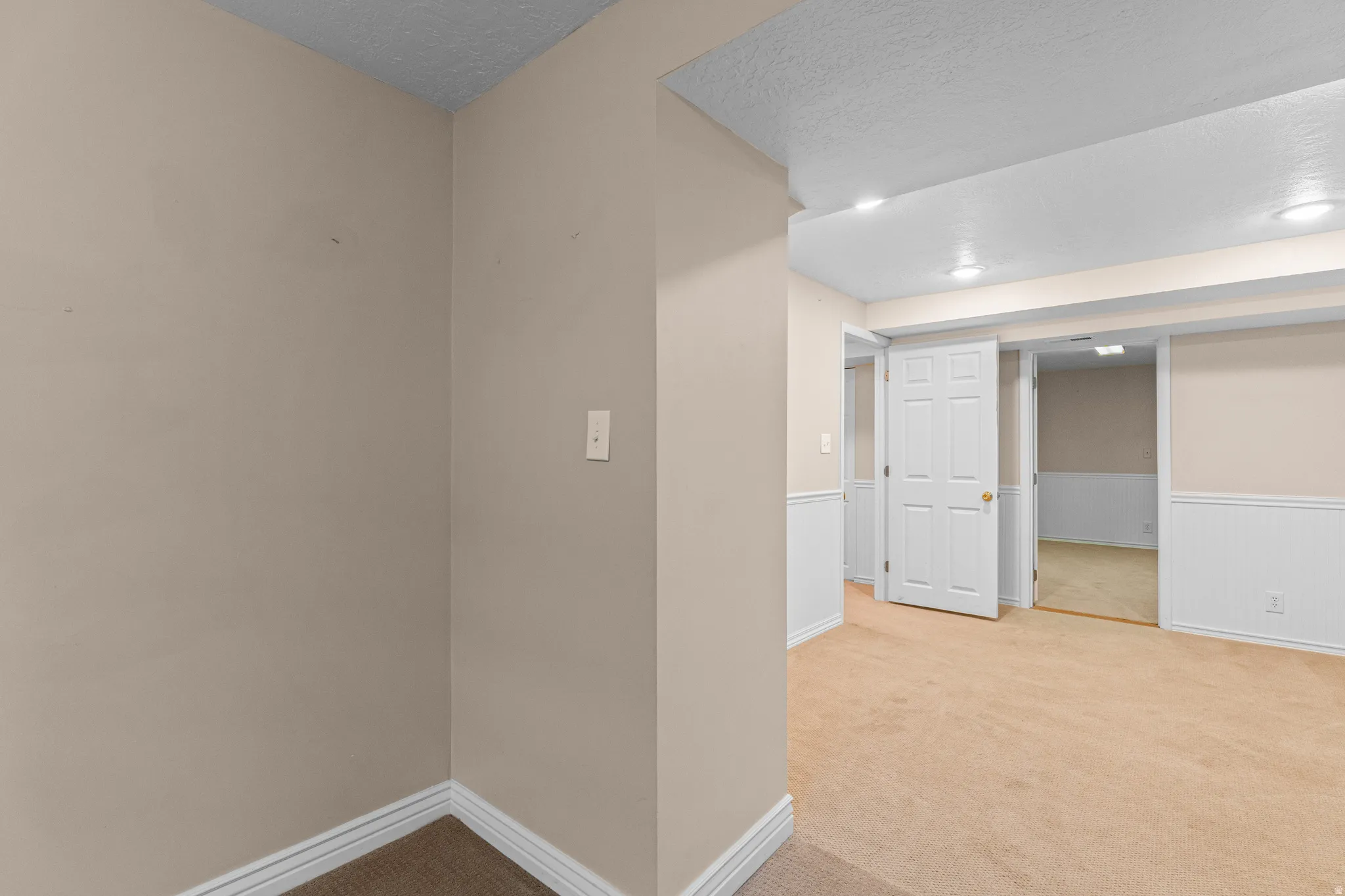 Carpeted room featuring neutral wall paint, white baseboards, recessed lighting, and a paneled white door