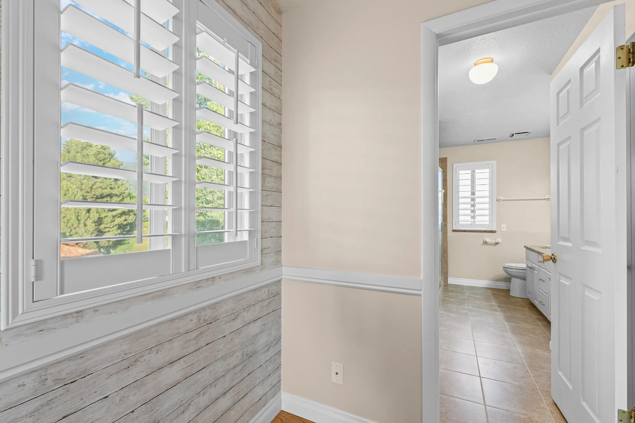 Hallway with shiplap wainscoting and a window featuring white plantation shutters