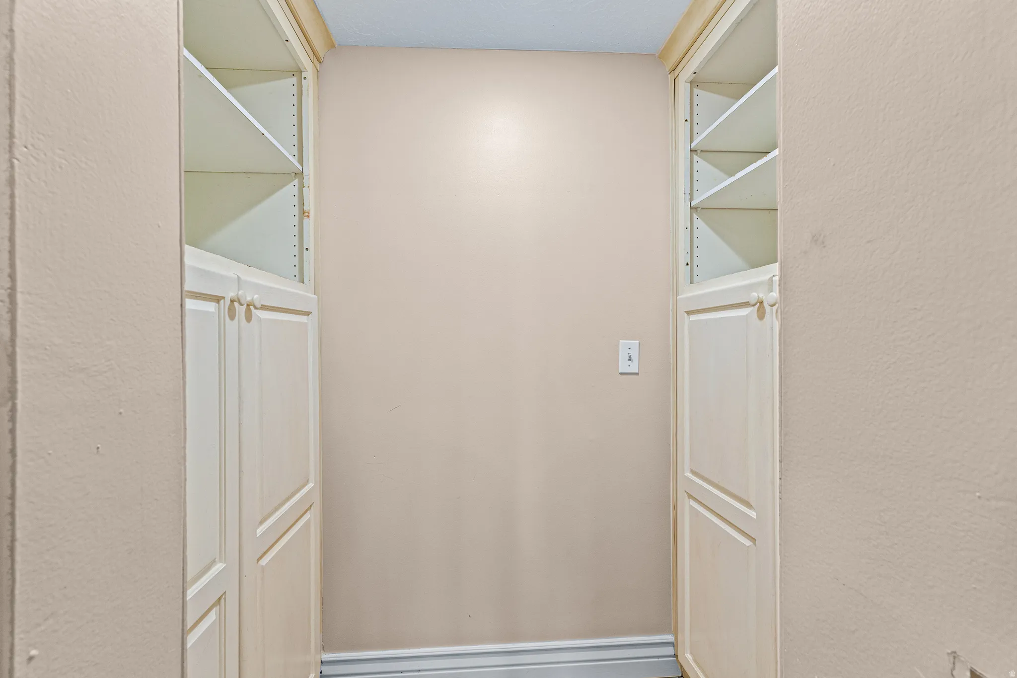 Built-in cabinetry with paneled doors and open shelving, featuring light-toned finishes and crown molding