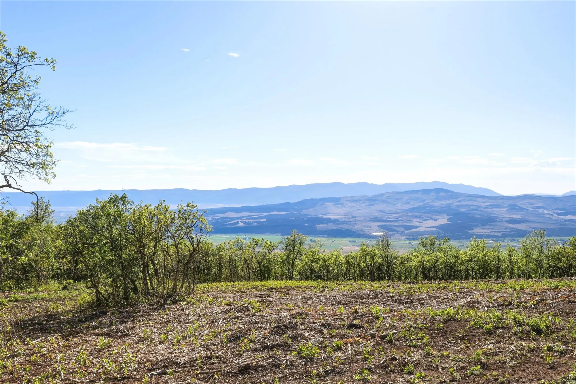 Expansive natural landscape featuring distant mountain ranges and a clear sky