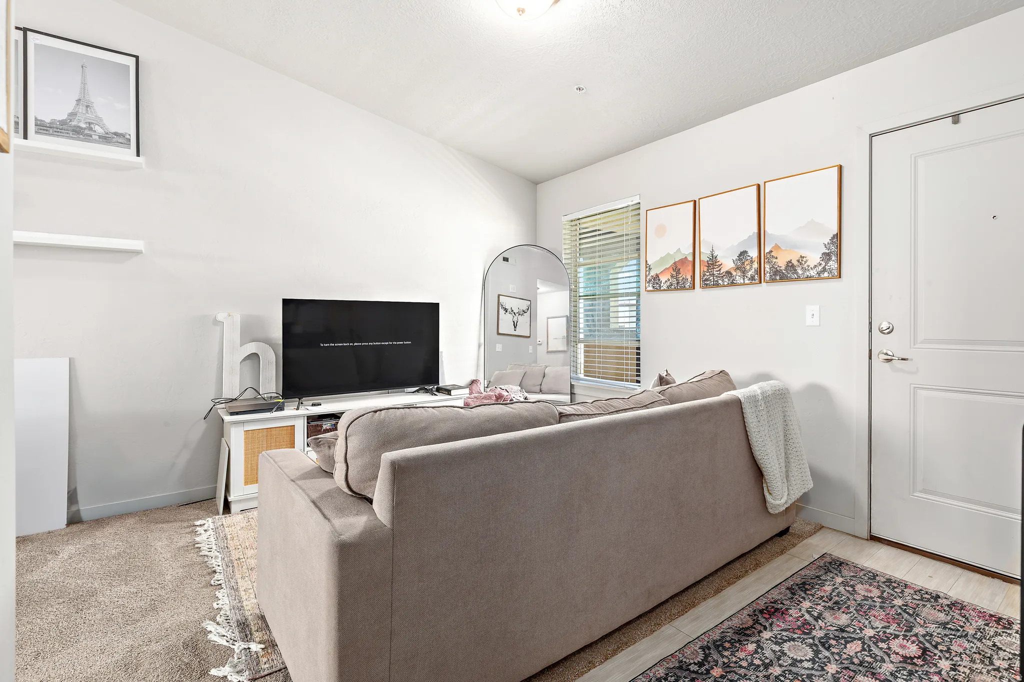 Living area featuring neutral wall tones, a paneled entry door, a window with blinds, and recessed lighting