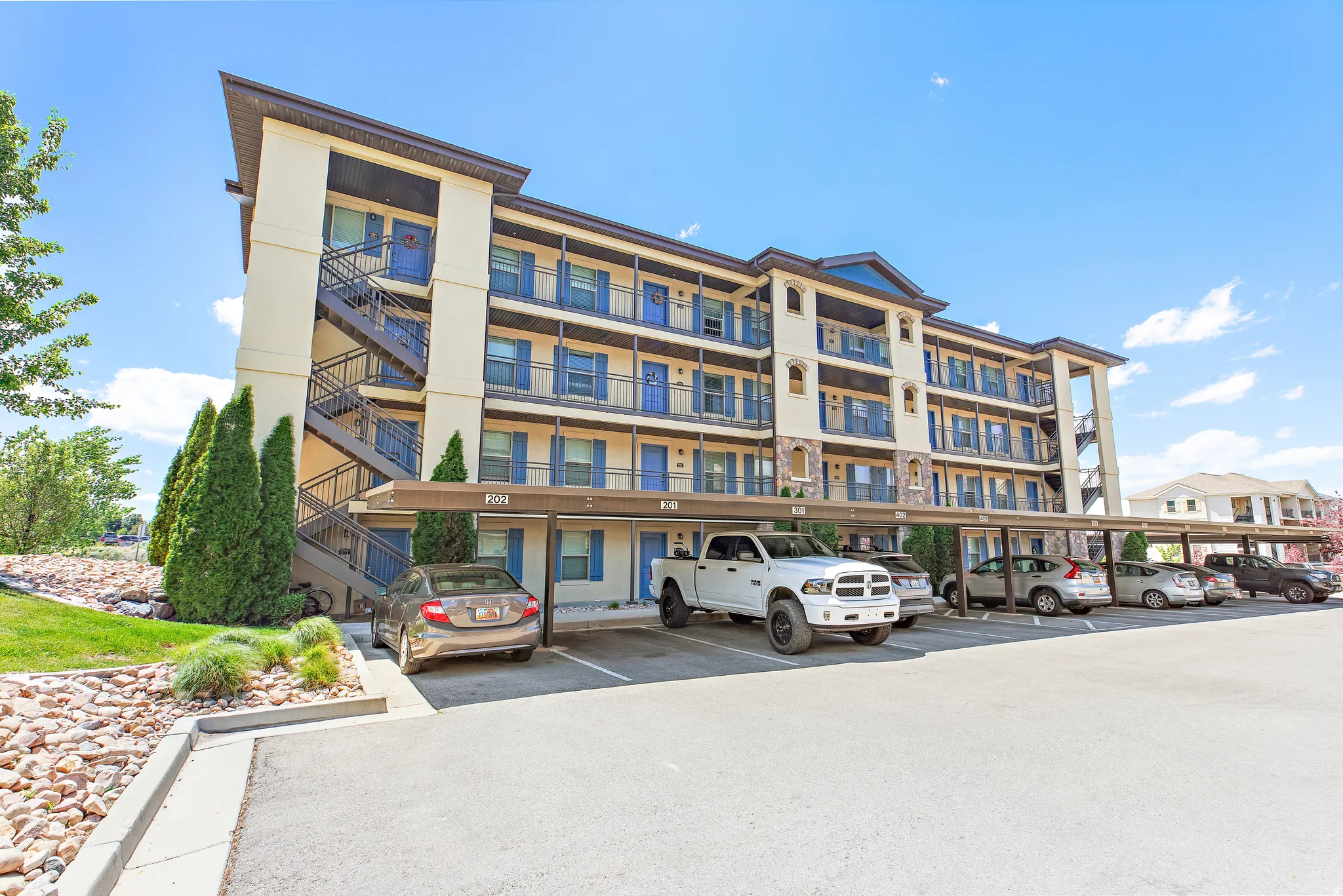 Multi-story building exterior featuring stucco siding and stone accents