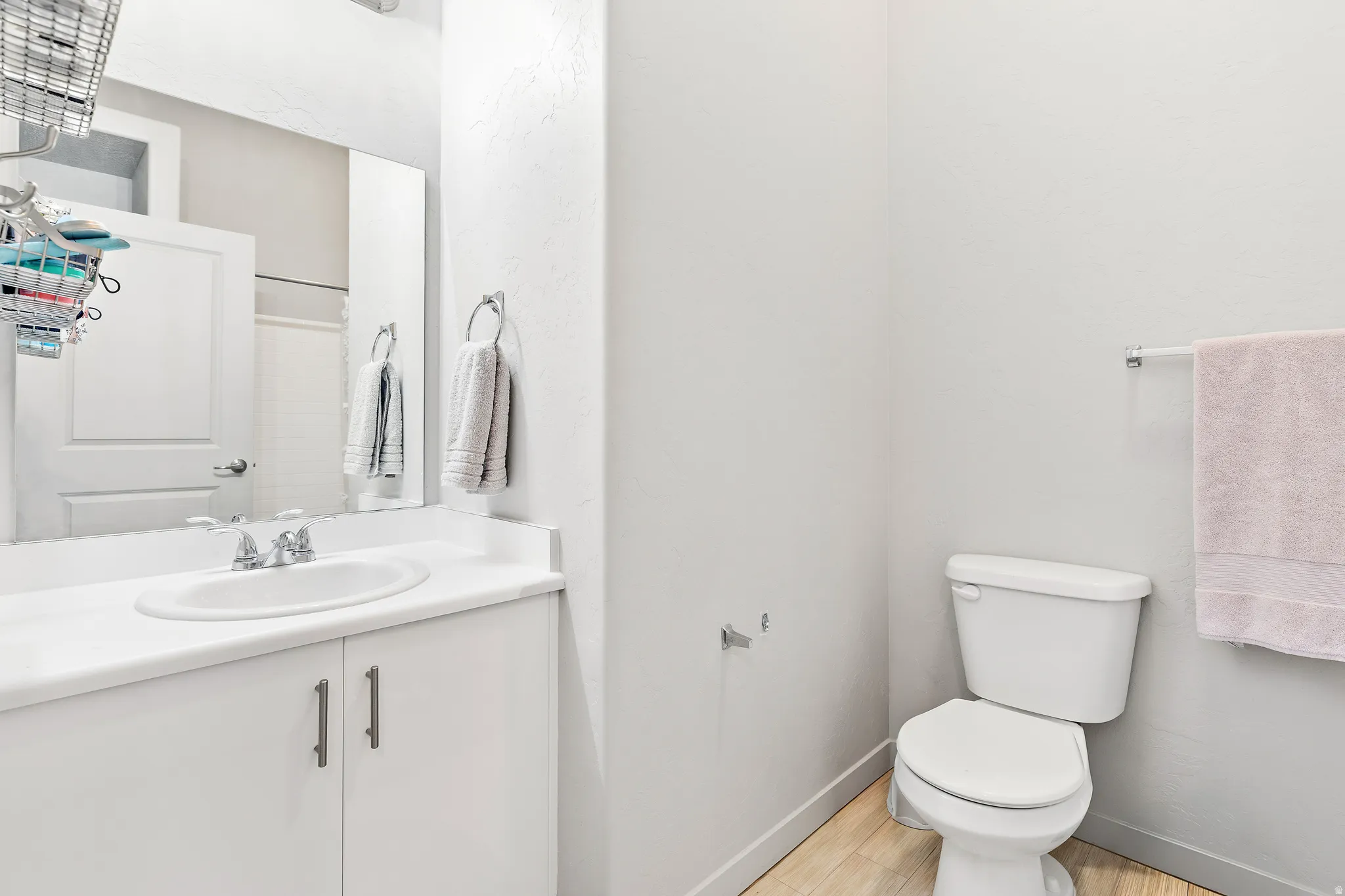Bathroom vanity featuring a white countertop with an integrated sink, polished chrome faucet, and white cabinetry with brushed nickel hardware