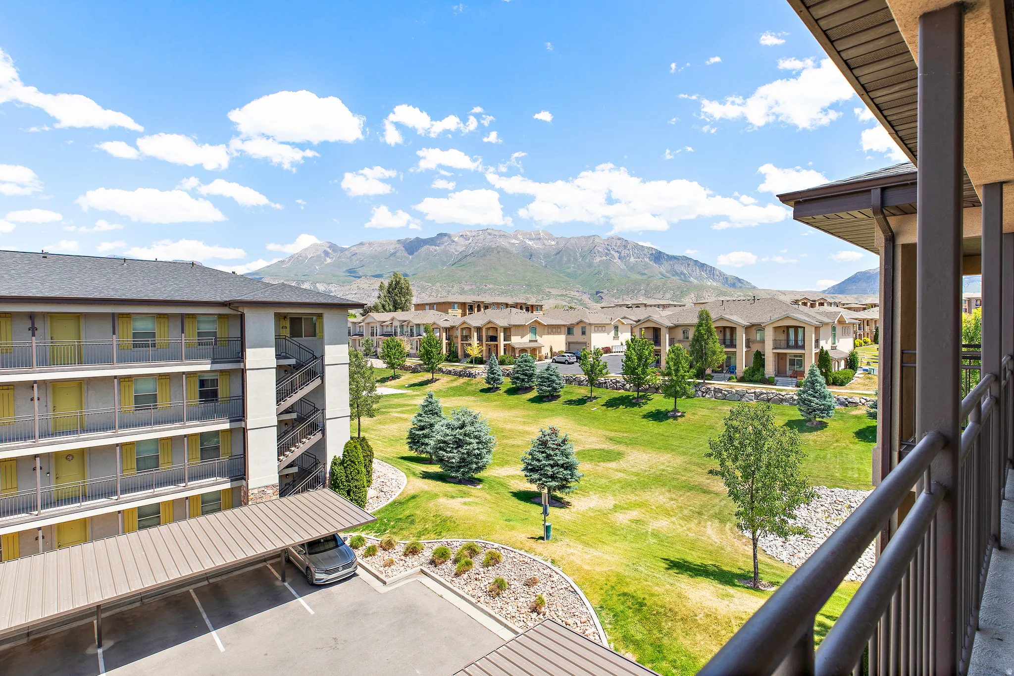 Balcony offering expansive views of surrounding mountains, green spaces, and community buildings