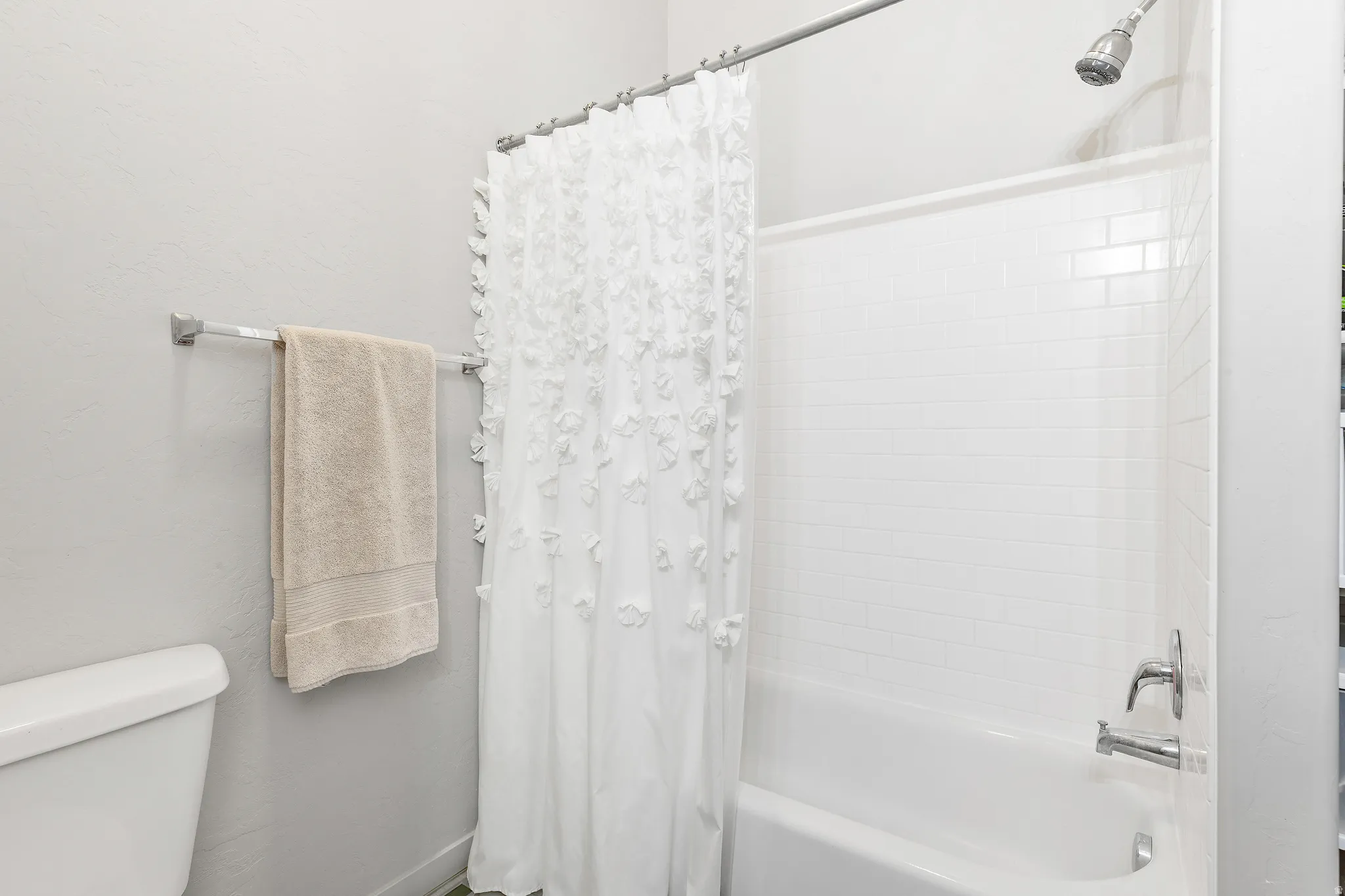 White subway tile shower surround with a chrome shower head and faucet