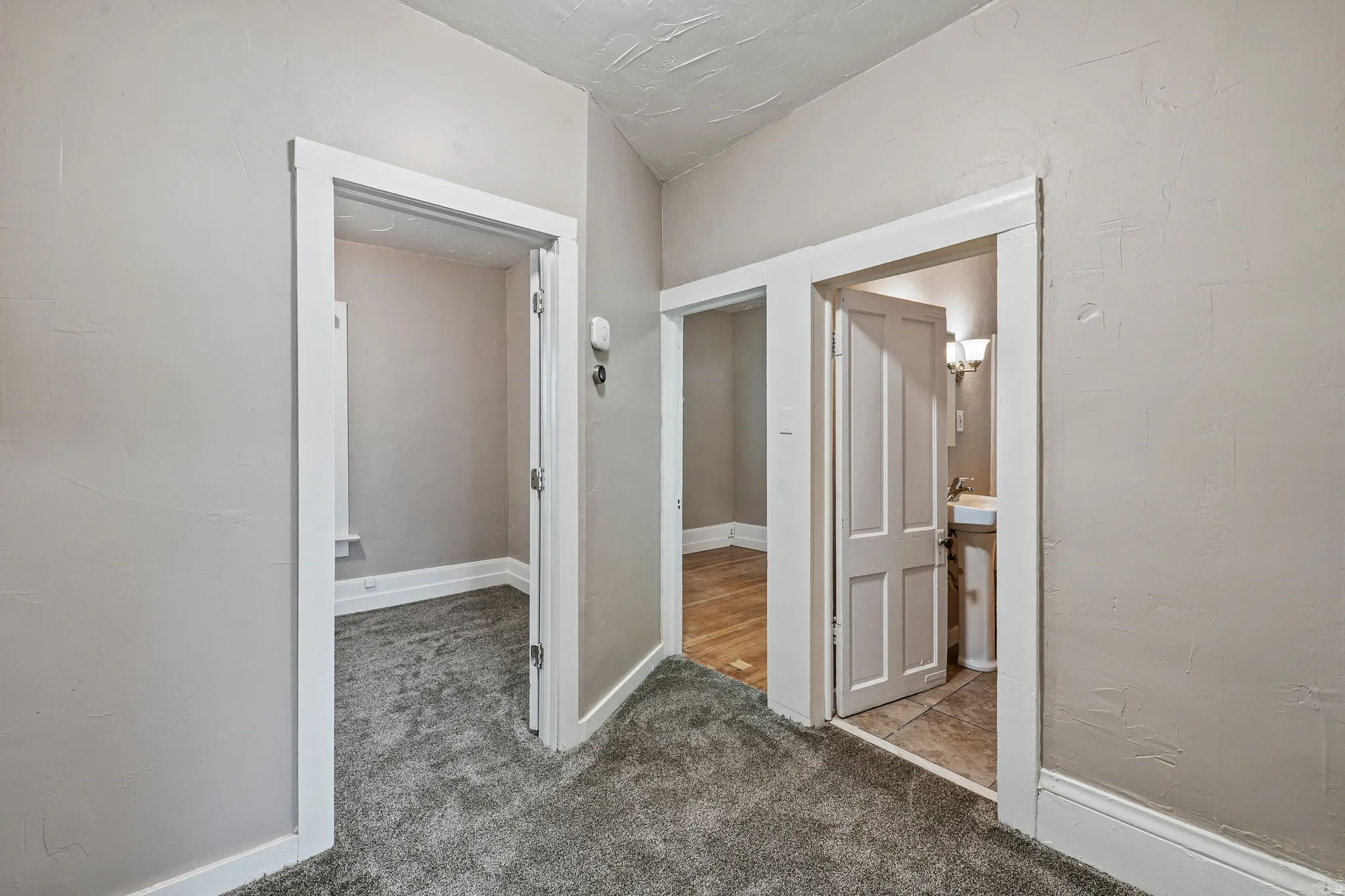 Interior hallway featuring neutral wall paint and gray carpet flooring