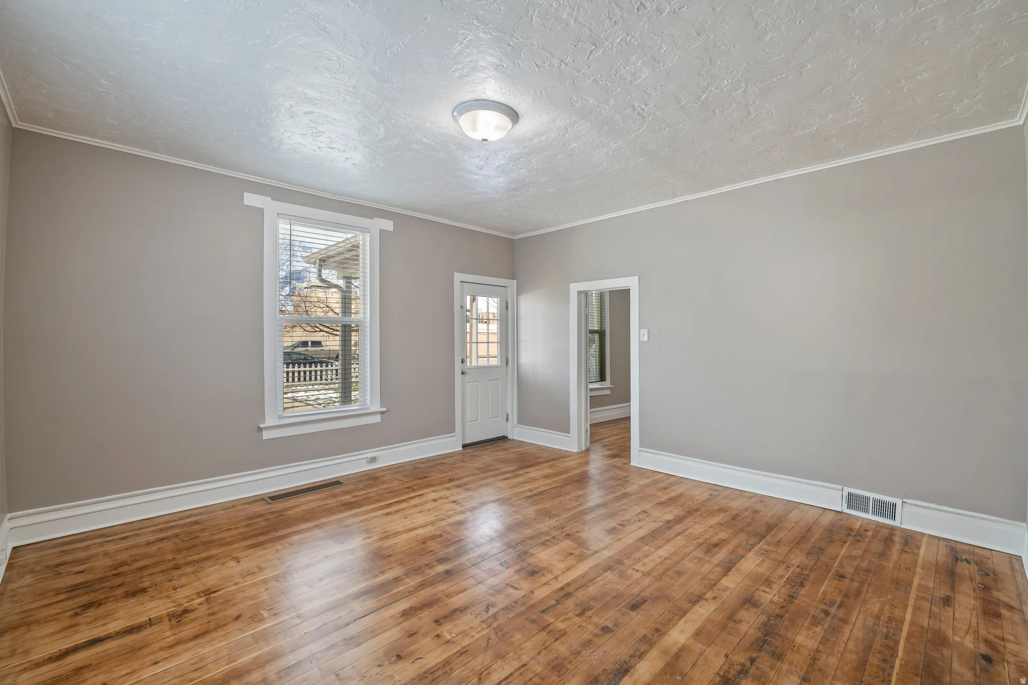 Spacious interior room featuring wood-finish flooring, neutral wall tones, and white trim