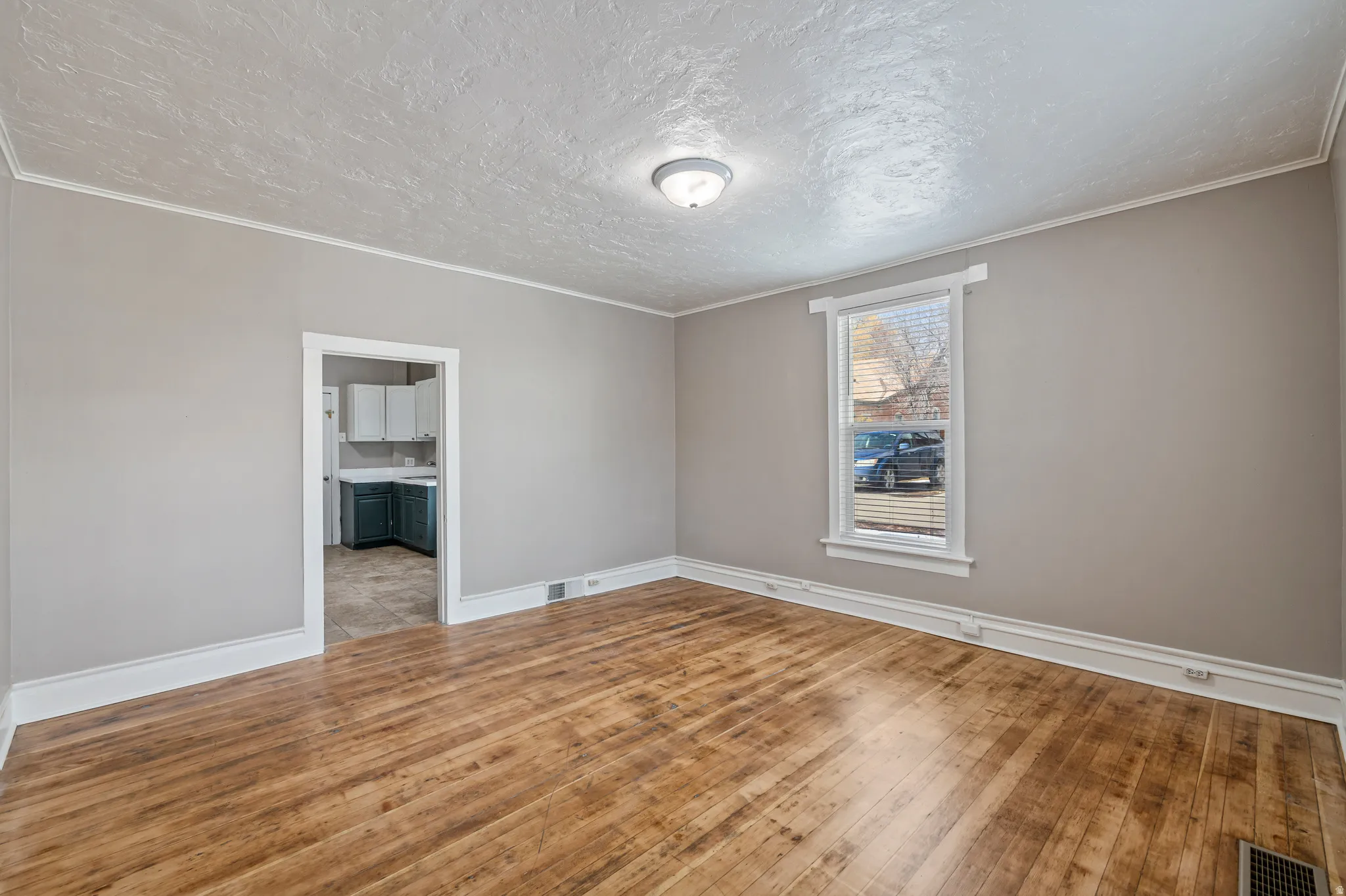 Spacious room with wood-finish flooring, light gray wall paint, and white trim
