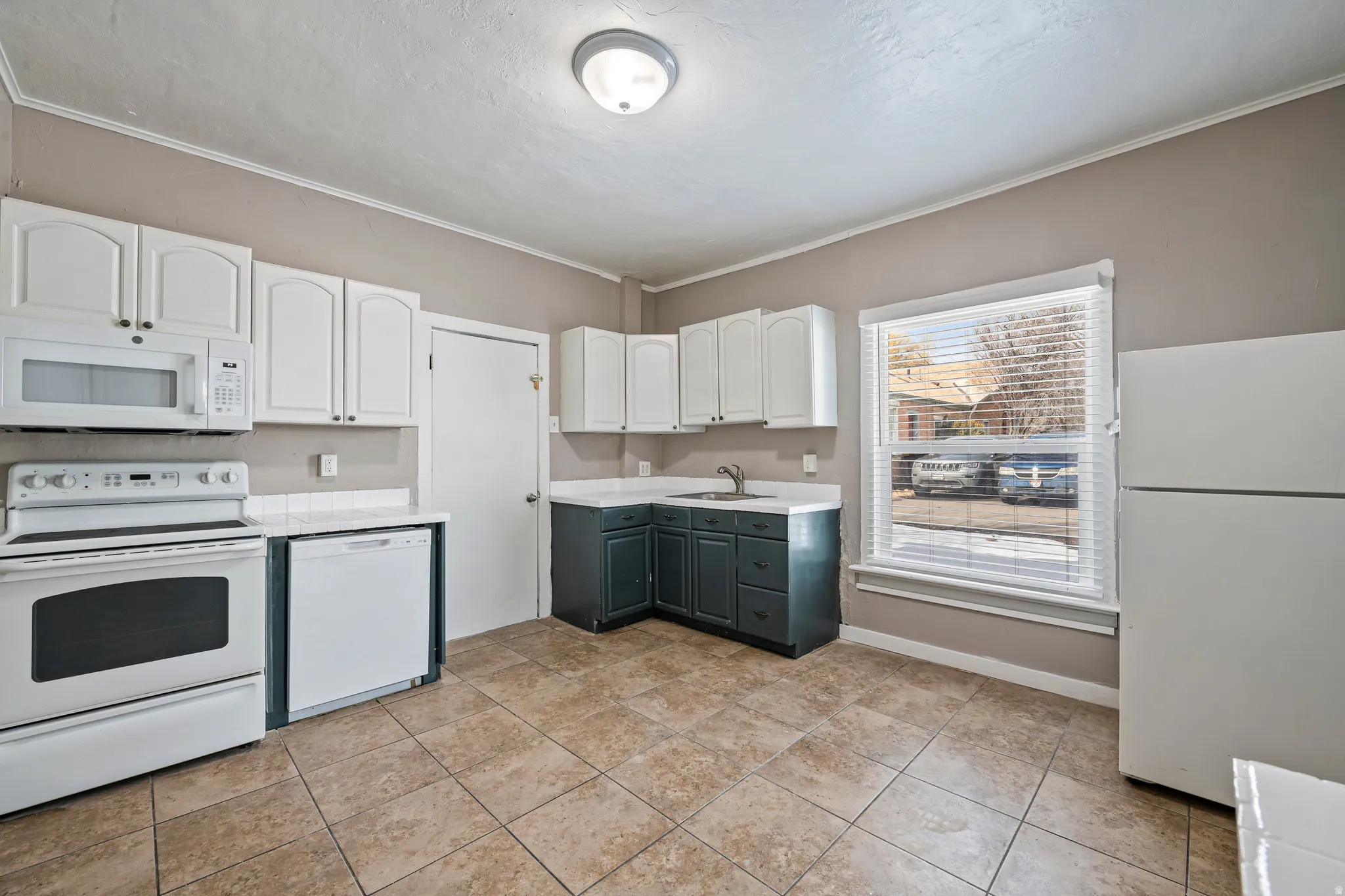 Kitchen featuring white upper cabinetry, contrasting dark lower cabinetry, and a white refrigerator