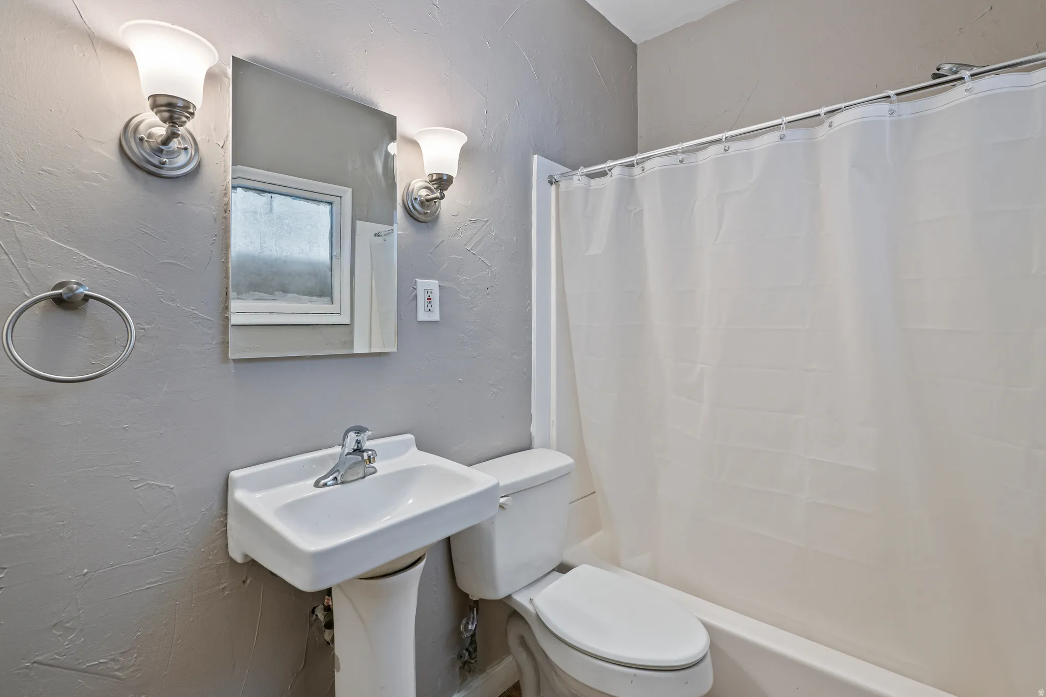 Pedestal sink with chrome faucet and polished nickel wall sconces