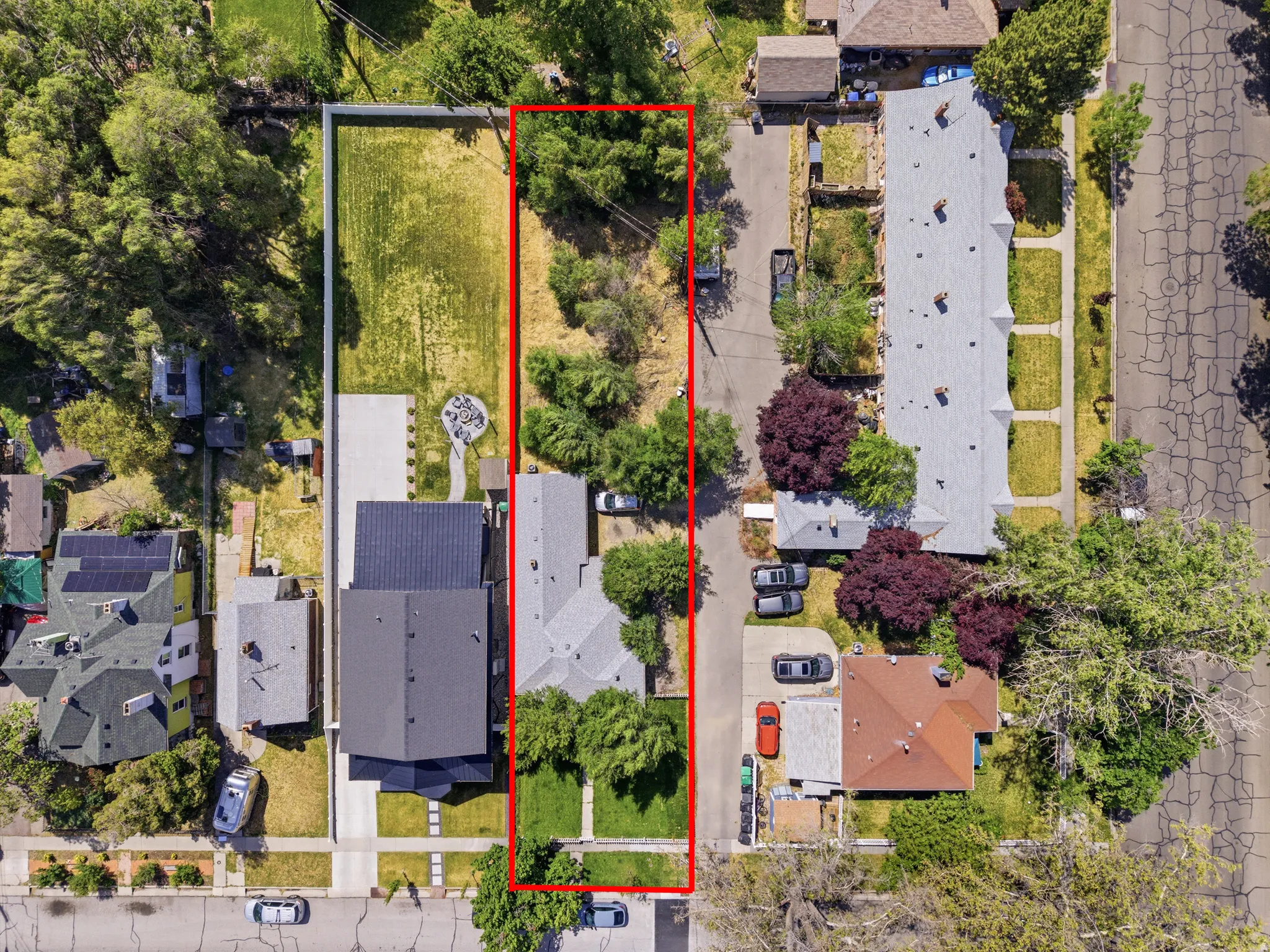 Expansive property featuring a elongated lot with mature trees, a manicured lawn, and a paved driveway