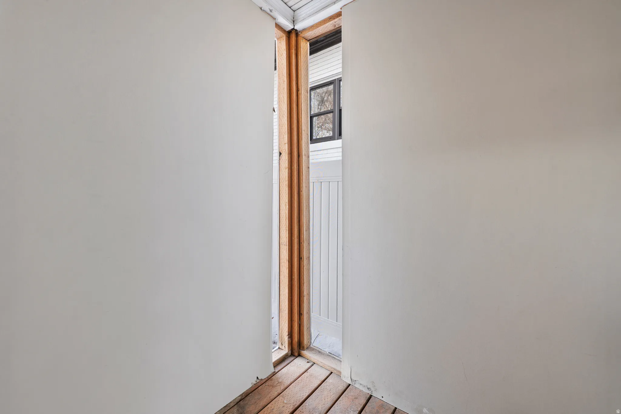 Entryway with wood-finish flooring, light-toned walls, and an exterior window with black framing