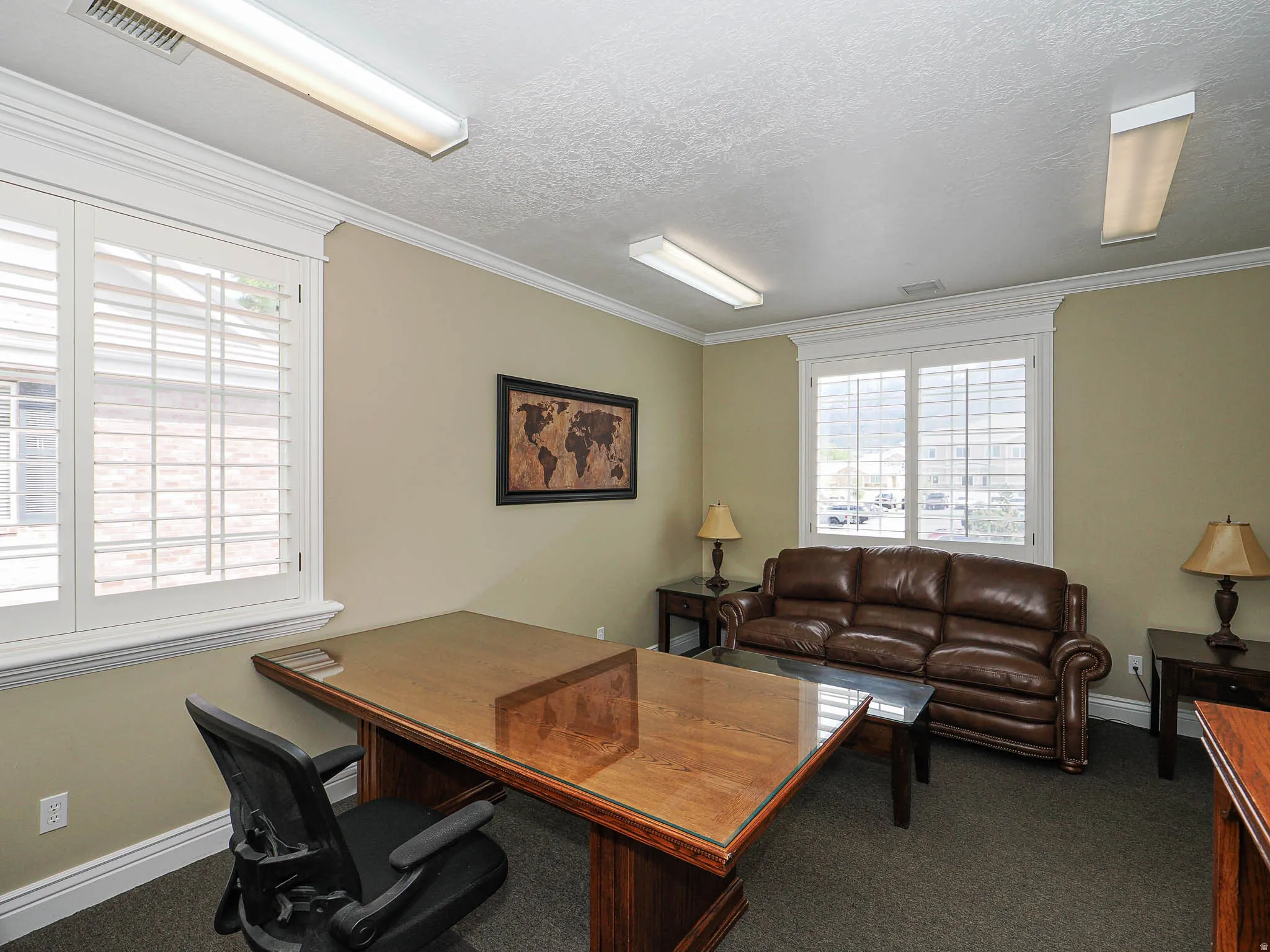 Office featuring dark colored carpet, crown molding, and a textured ceiling