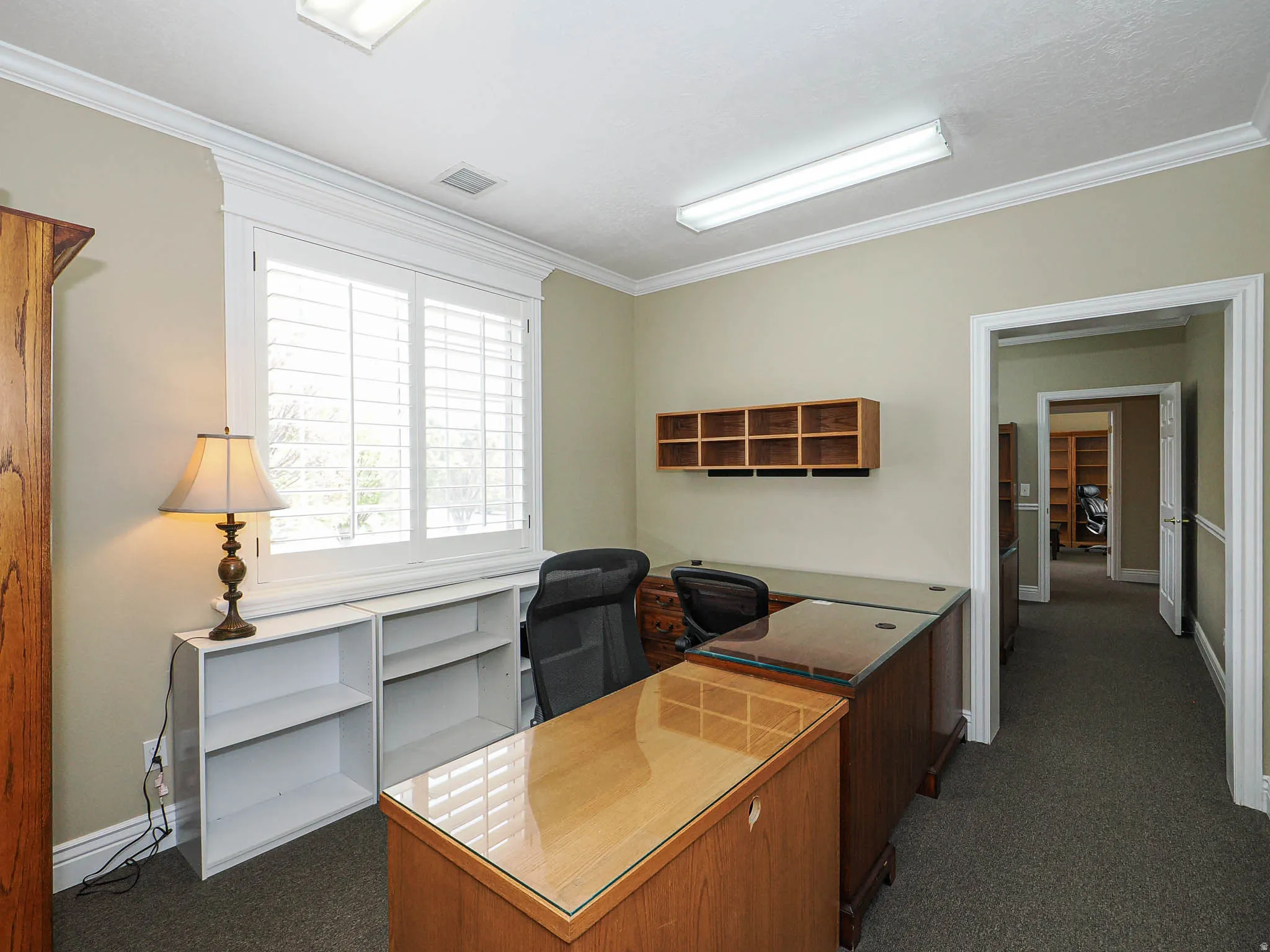 Office featuring dark colored carpet and crown molding