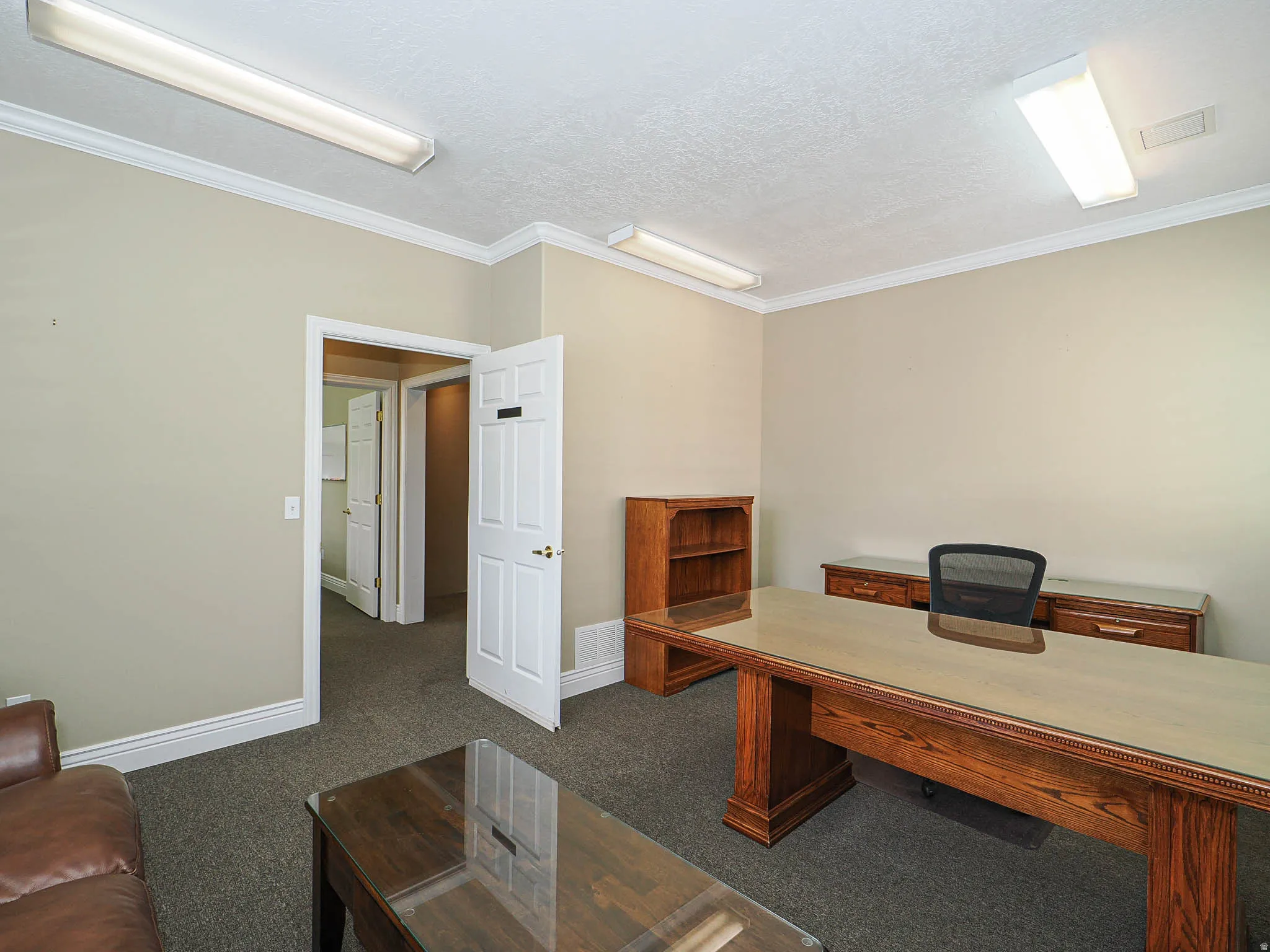 Office space featuring crown molding, dark colored carpet, and a textured ceiling