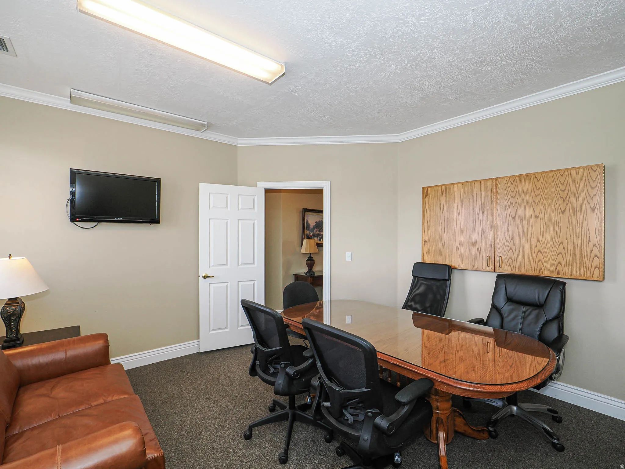 Home office featuring dark carpet, crown molding, and a textured ceiling