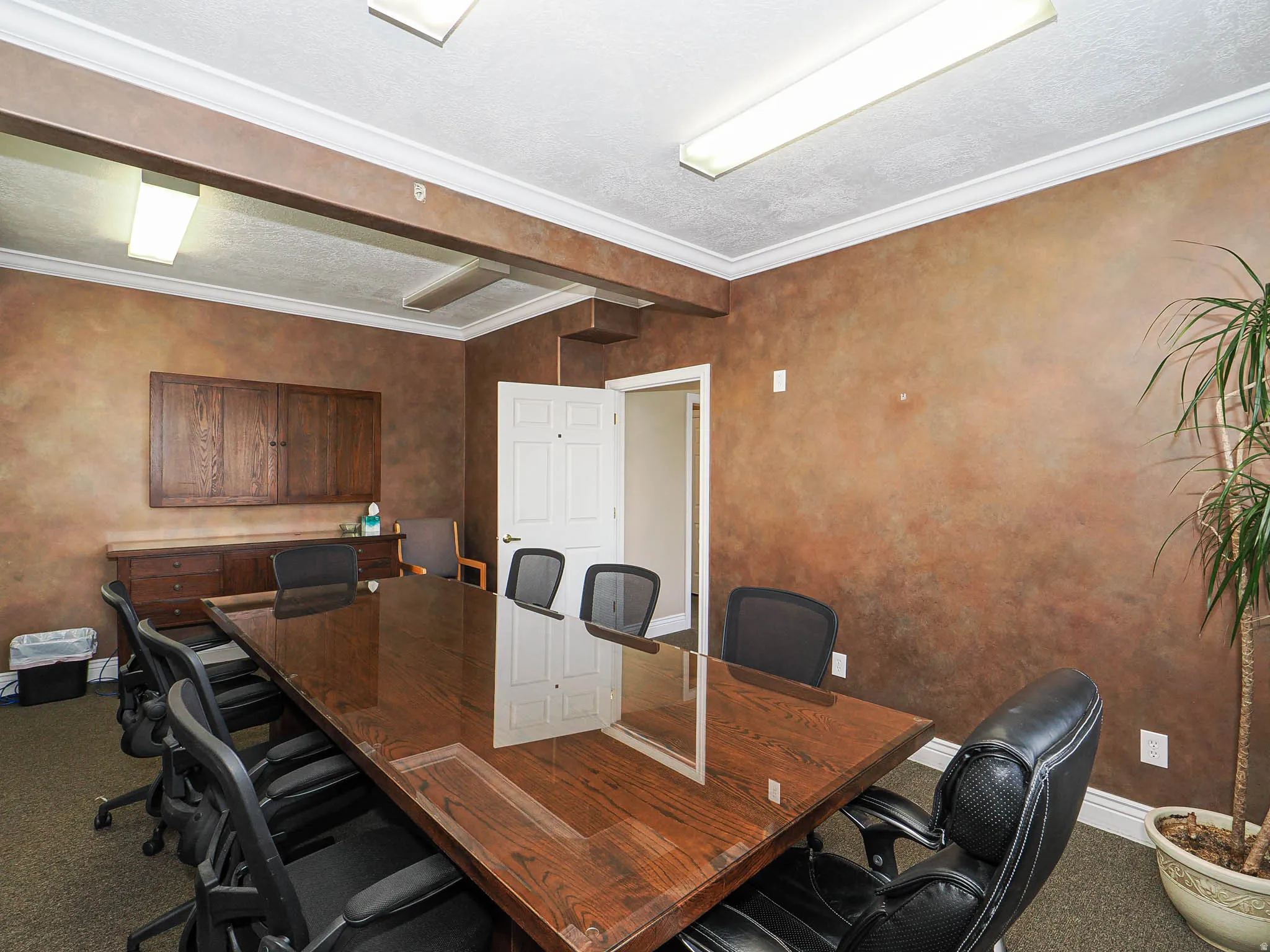 Home office with crown molding, a textured ceiling, dark carpet, and a textured wall