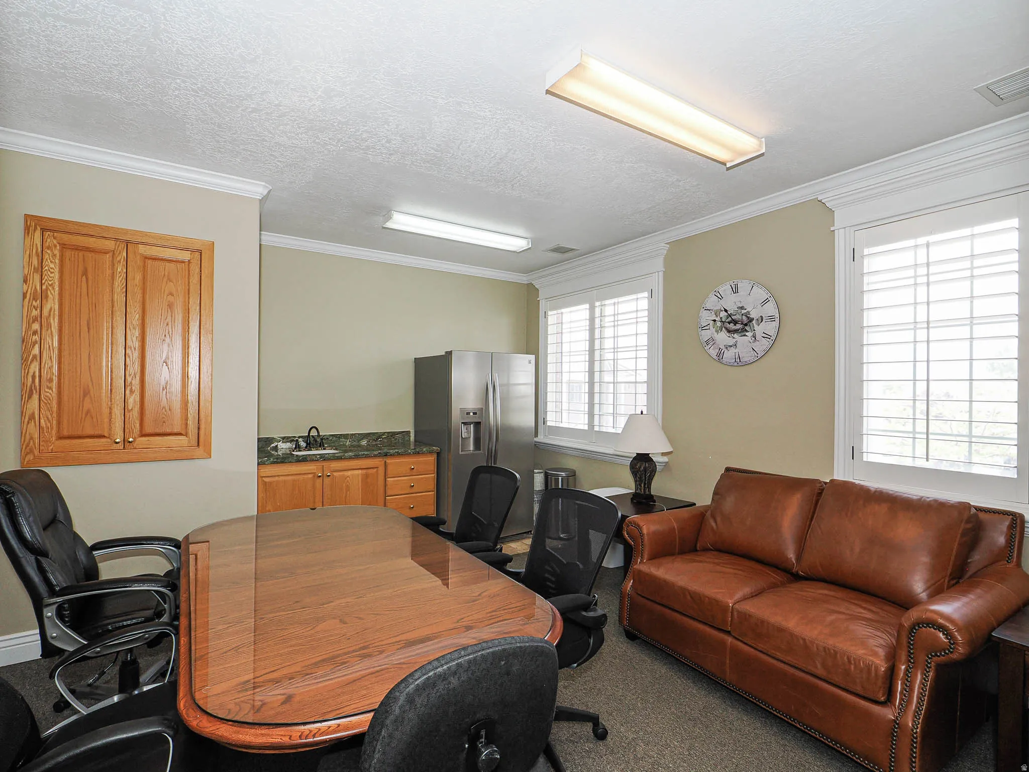 Carpeted office space with ornamental molding and a textured ceiling