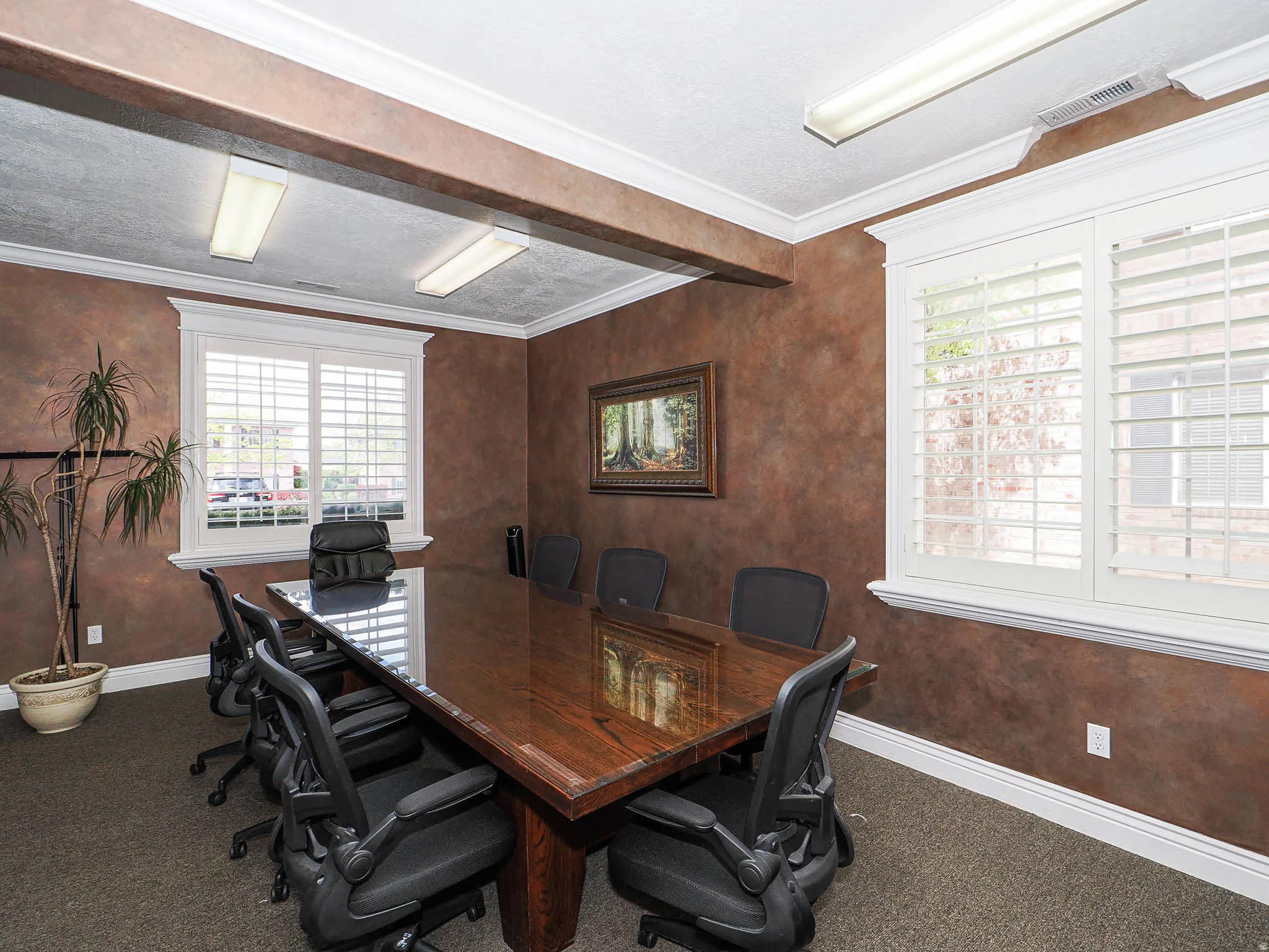 Office area with ornamental molding and dark colored carpet