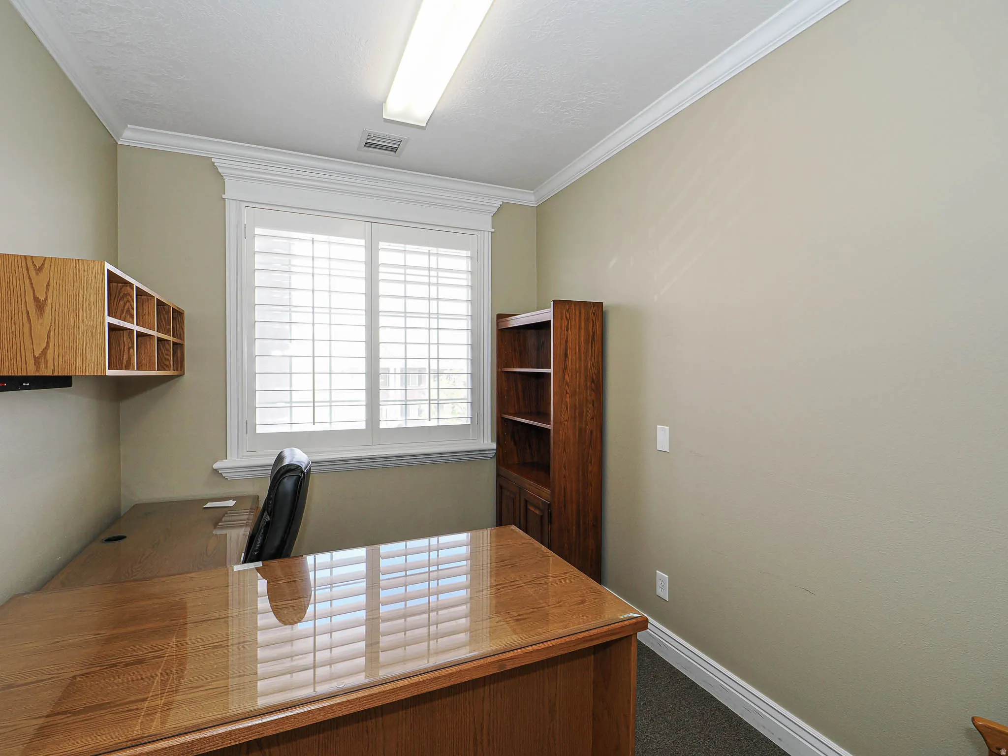 Office with dark colored carpet and crown molding