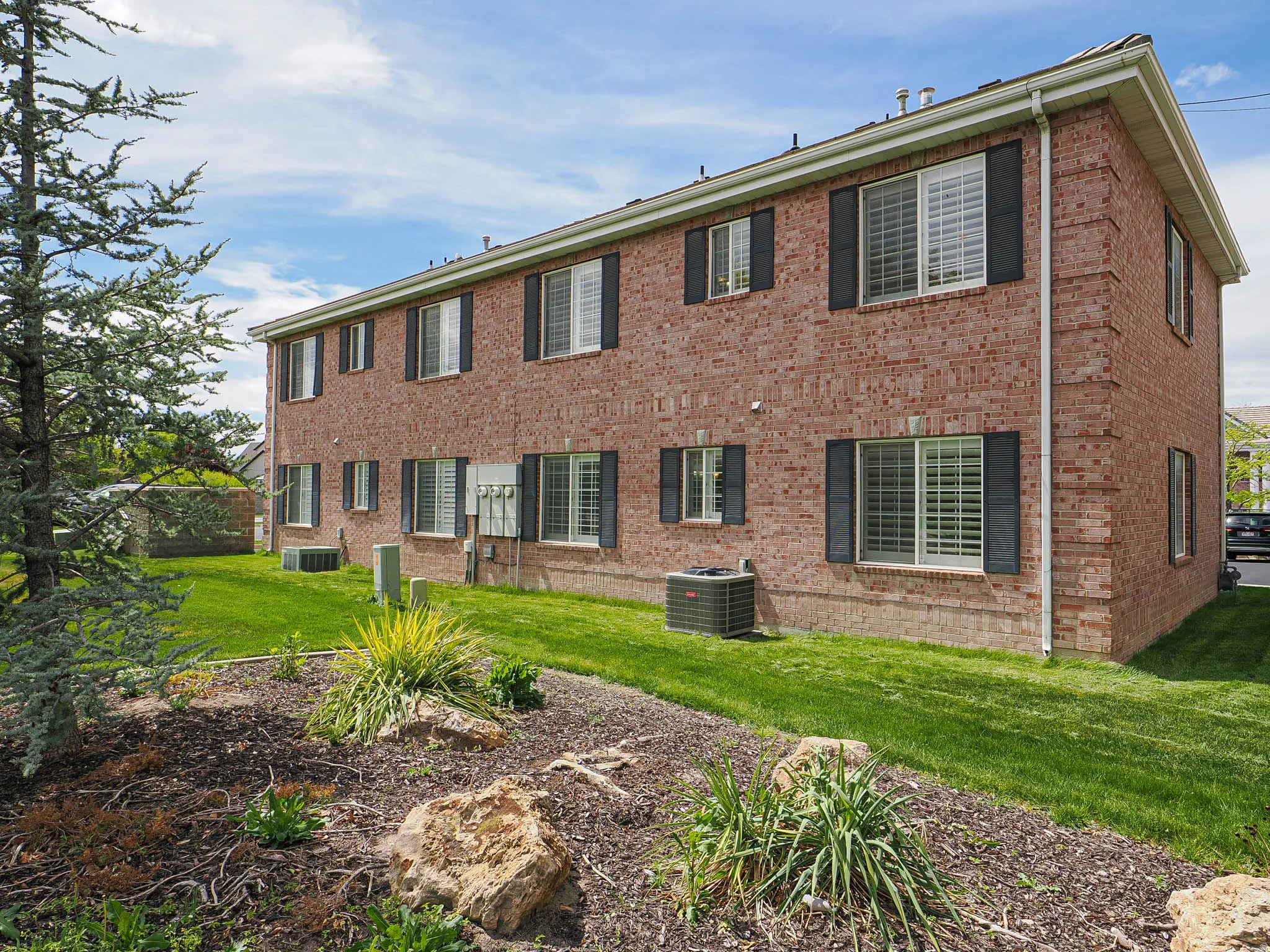 Rear view of property featuring brick siding and a lawn