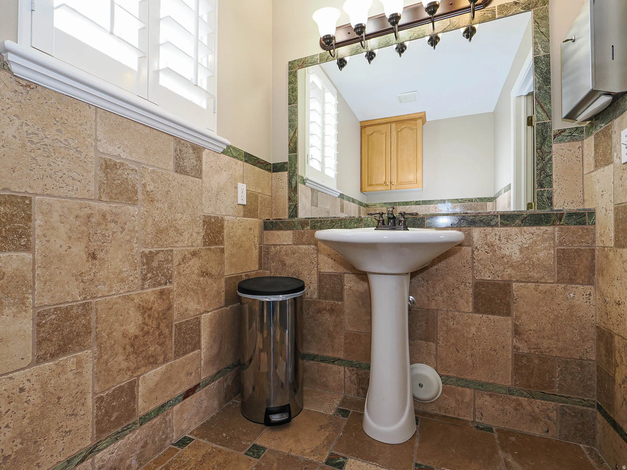 Bathroom with tile walls, wainscoting, and stone tile flooring