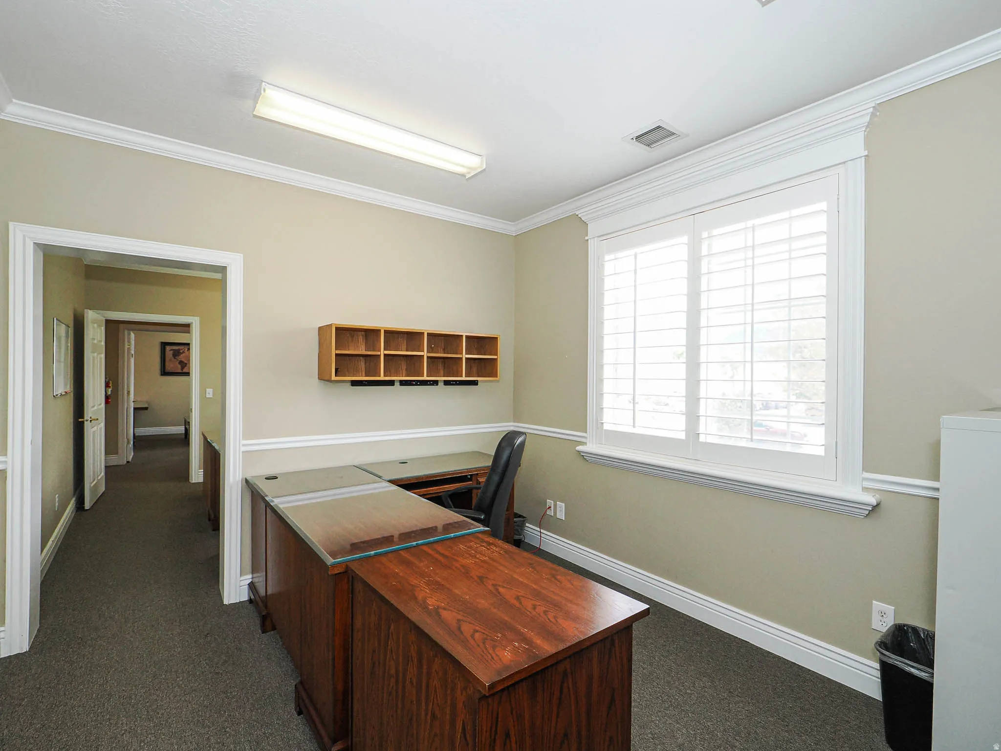 Home office with dark colored carpet and ornamental molding