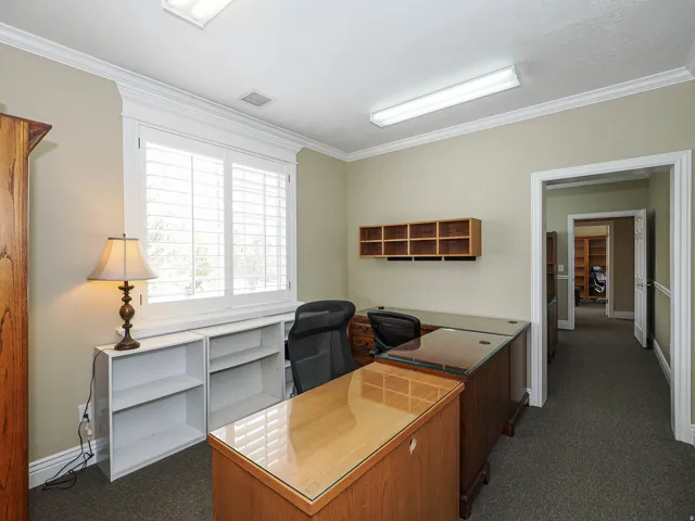 Office featuring dark colored carpet and crown molding