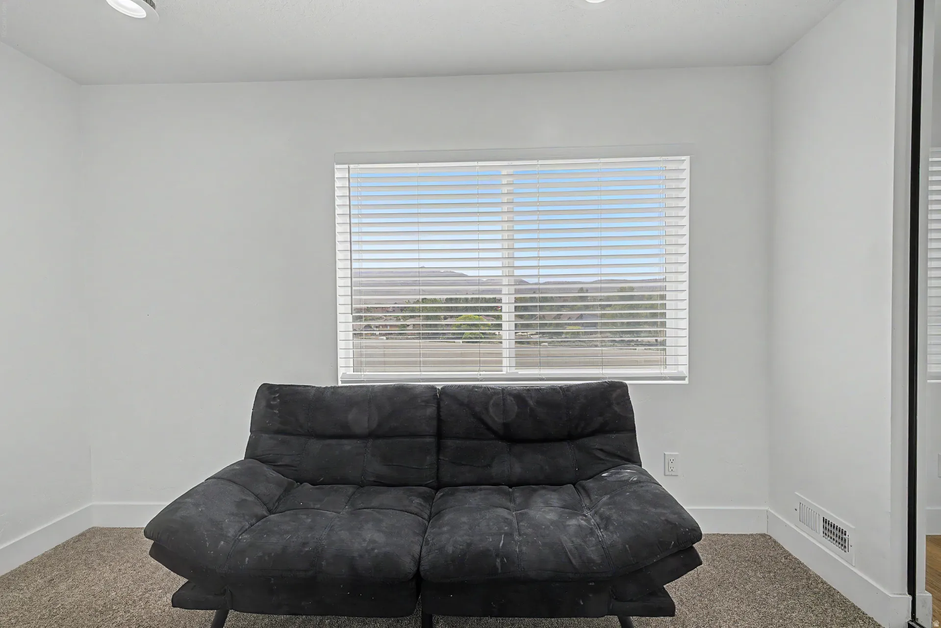 Basement bedroom Bright room with a large window featuring horizontal blinds