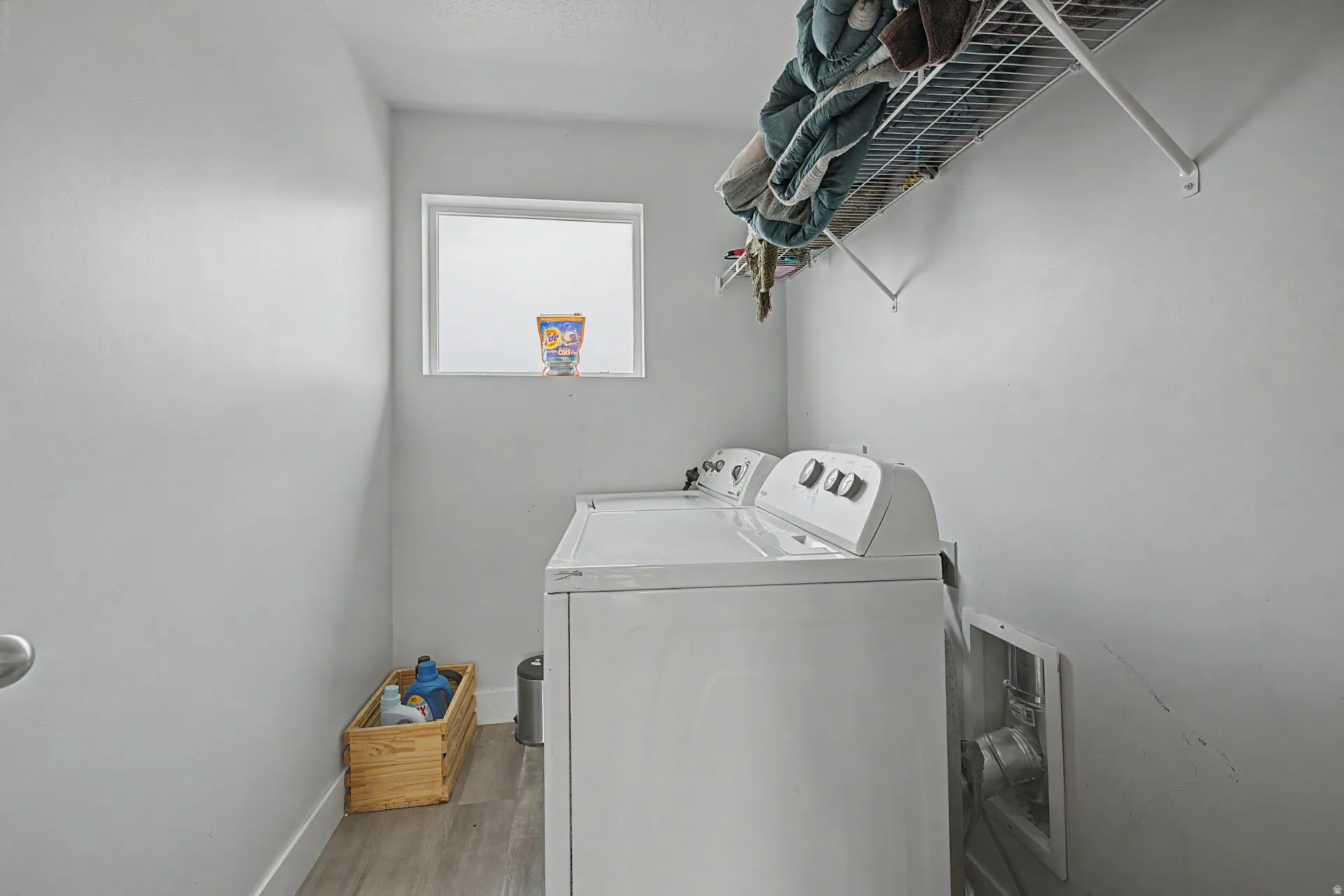 Laundry area featuring a window, wire shelving, and wood-finish flooring
