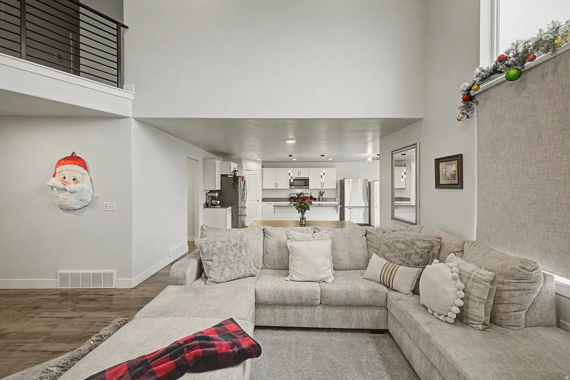 Open-concept living area featuring a two-story ceiling, wood-finish flooring, and a second-level interior balcony with metal railing