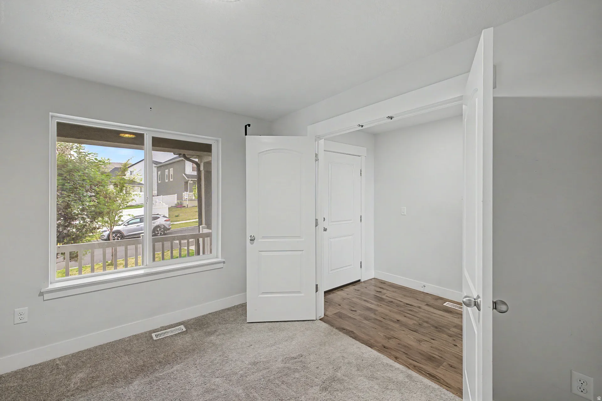 Windowed room featuring plush gray carpeting, a white trim package, and light gray wall paint
