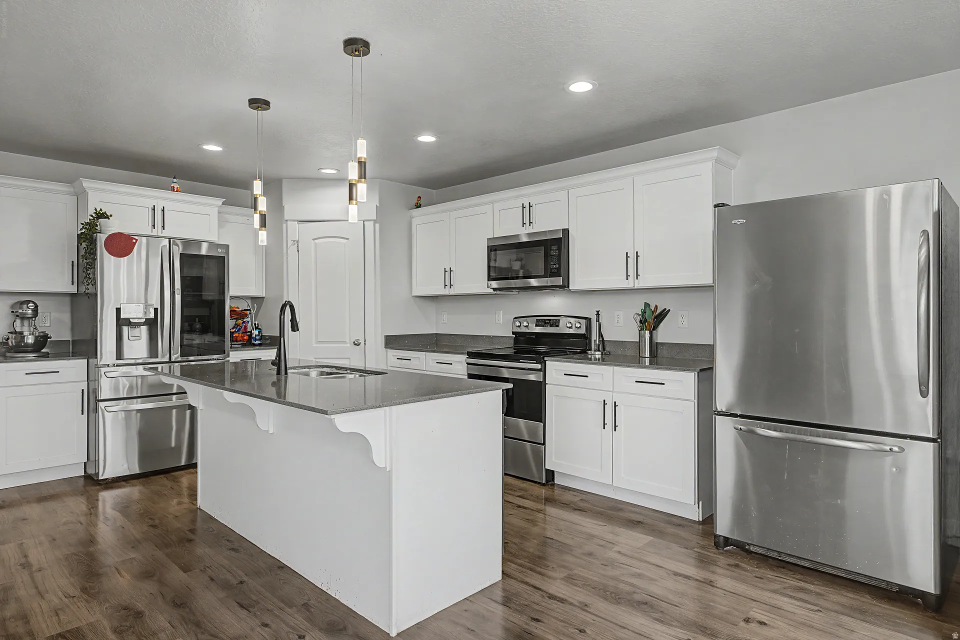 Contemporary kitchen featuring white cabinetry, dark countertops, and wood-finish flooring