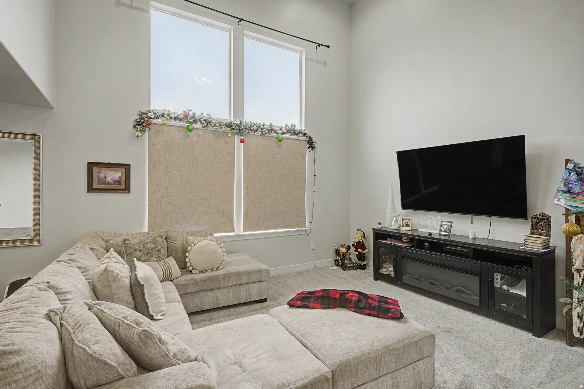 Living space featuring high ceilings, tall windows with roller shades, and light gray wall paint