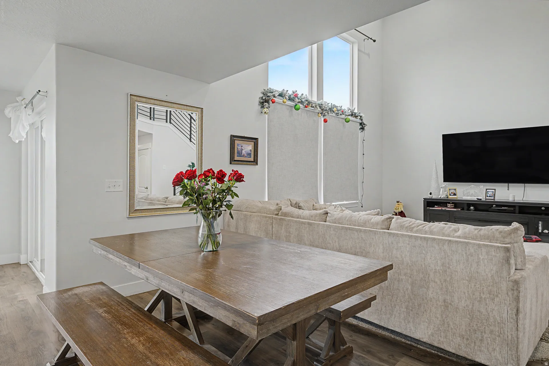 Open-concept living space featuring high ceilings, wood-finish flooring, and large windows providing ample natural light