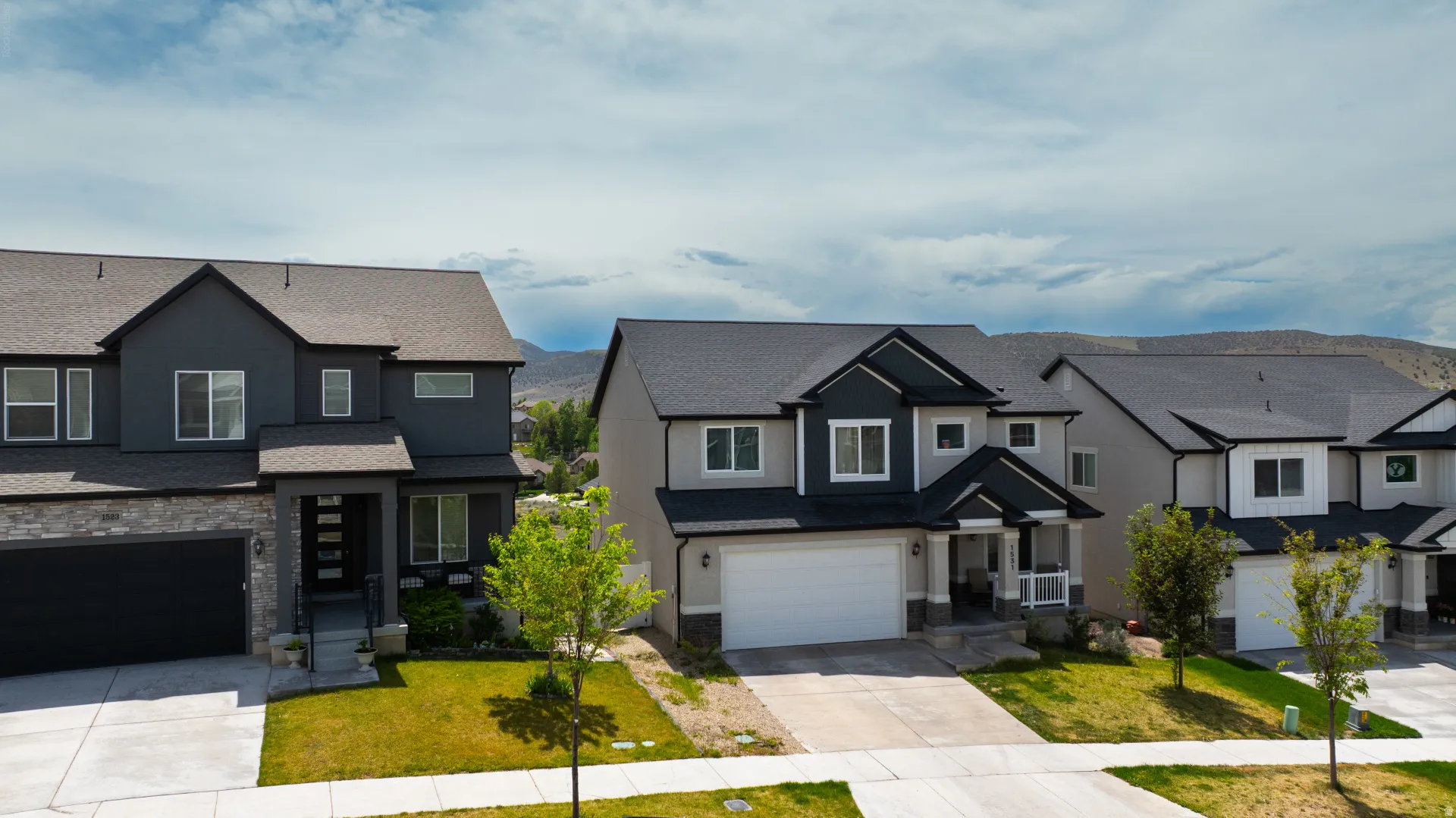 Contemporary residence featuring a two-car garage, stone accents, and dark gray siding