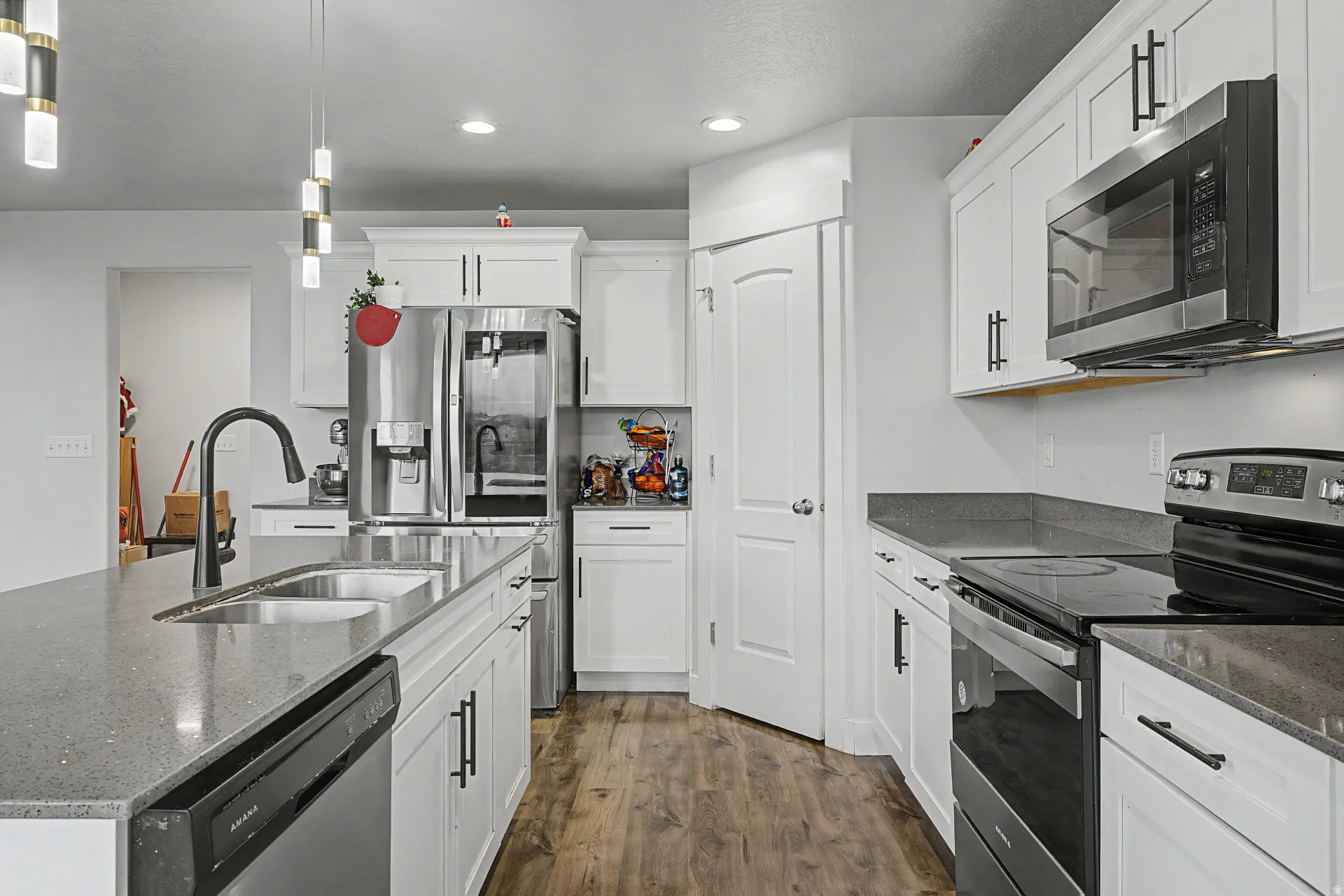 Modern kitchen featuring white cabinetry, wood-finish flooring, a stainless steel refrigerator, and a built-in microwave