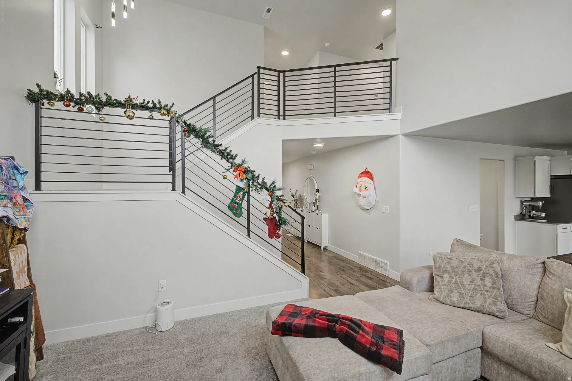 Two-story living area featuring a prominent staircase with black metal horizontal railings and a matching second-story landing