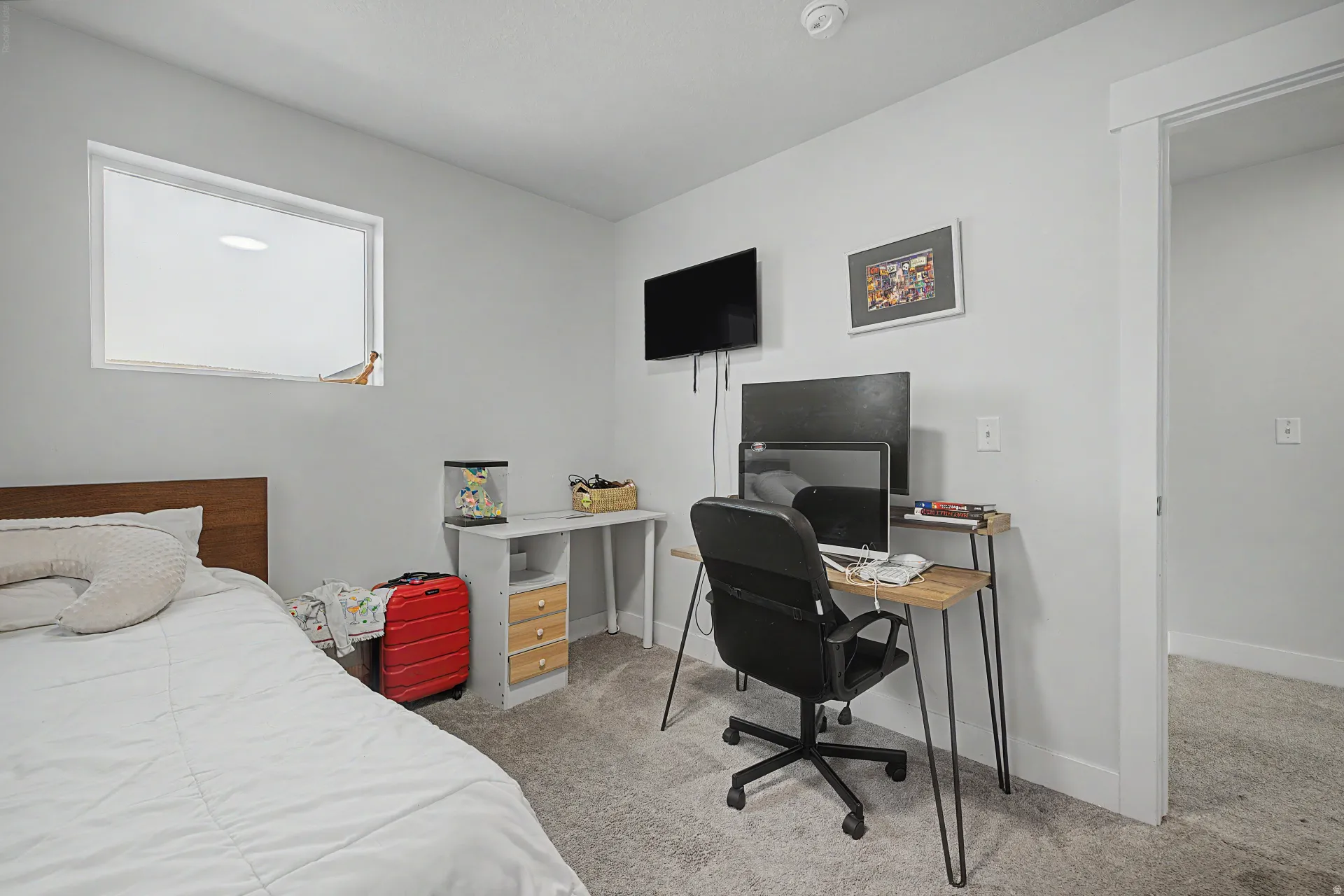 Carpeted room featuring a white-trimmed window, neutral wall paint, and a built-in wall television mount