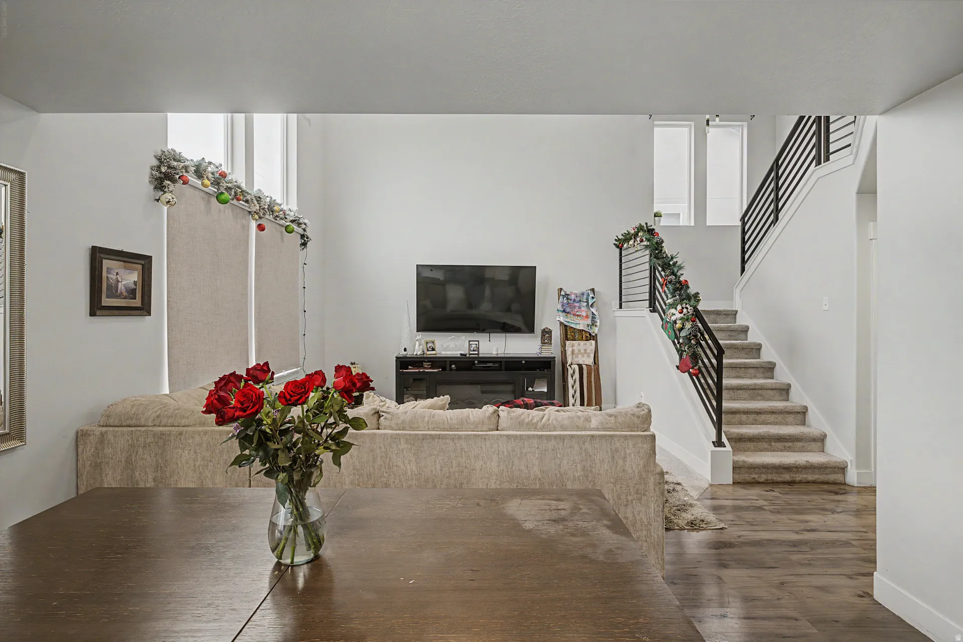 Open-concept living space featuring a modern staircase with black metal railings, high ceilings, and tall windows
