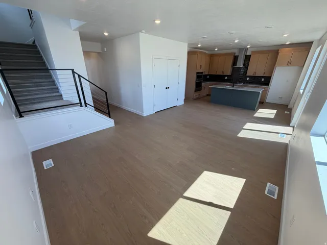 Open-concept living area featuring wood-finish flooring, a modern kitchen with light wood cabinetry, a contrasting island, and built-in appliances