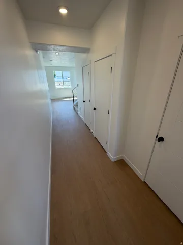 Wood-finish flooring throughout, bright white walls, modern interior doors with matte black hardware, and recessed lighting