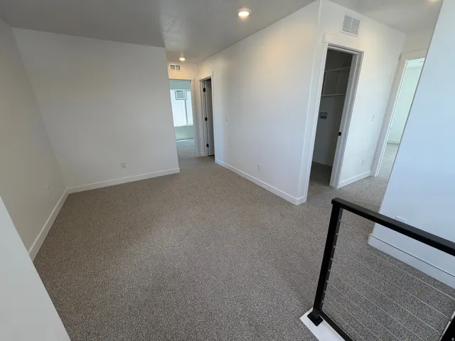 Neutral carpeted flooring with white wall finishes, recessed lighting, and a metal cable railing system