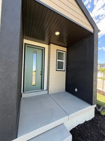 Covered entryway featuring a recessed light fixture, a light green door with a vertical window, and horizontal siding accents