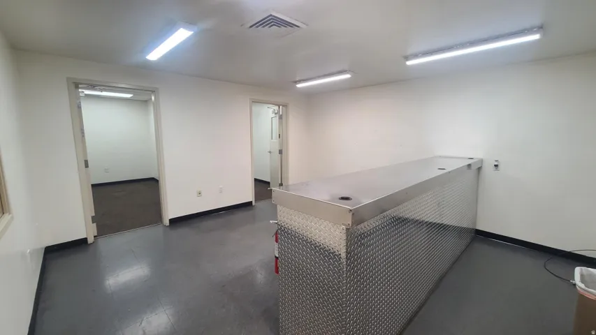 Spacious interior with two open doorways, dark flooring, and a large diamond plate metal counter