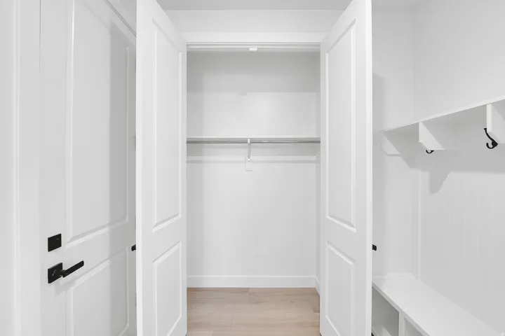Built-in storage solutions featuring a bifold closet with shelving and hanging rod, and a mudroom-style bench with cubbies and hooks
