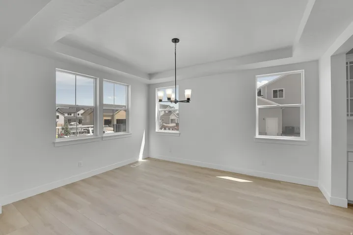 Spacious room with coffered ceiling, light wood-finish flooring, and multiple windows providing ample ambient light