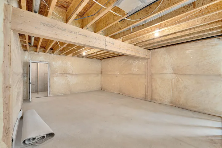 Unfinished lower level featuring an exposed wood joist ceiling, concrete flooring, and insulated walls