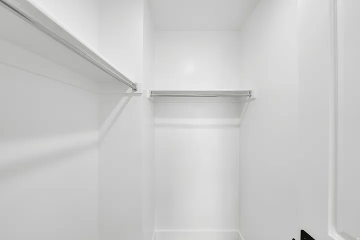 White interior closet with multiple hanging rods and integrated shelving