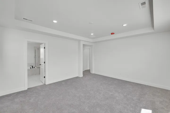 Recessed lighting illuminates this spacious room featuring plush gray carpeting